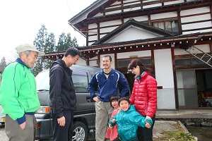 引っ越した家の前で談笑する浦田さん家族と住民